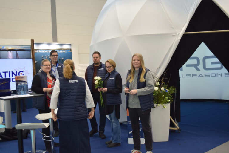 Picture taken from Boating Finland stand at Boot Düsseldorf exhibition. Picture contains a gray dome, six staff members and a screen.